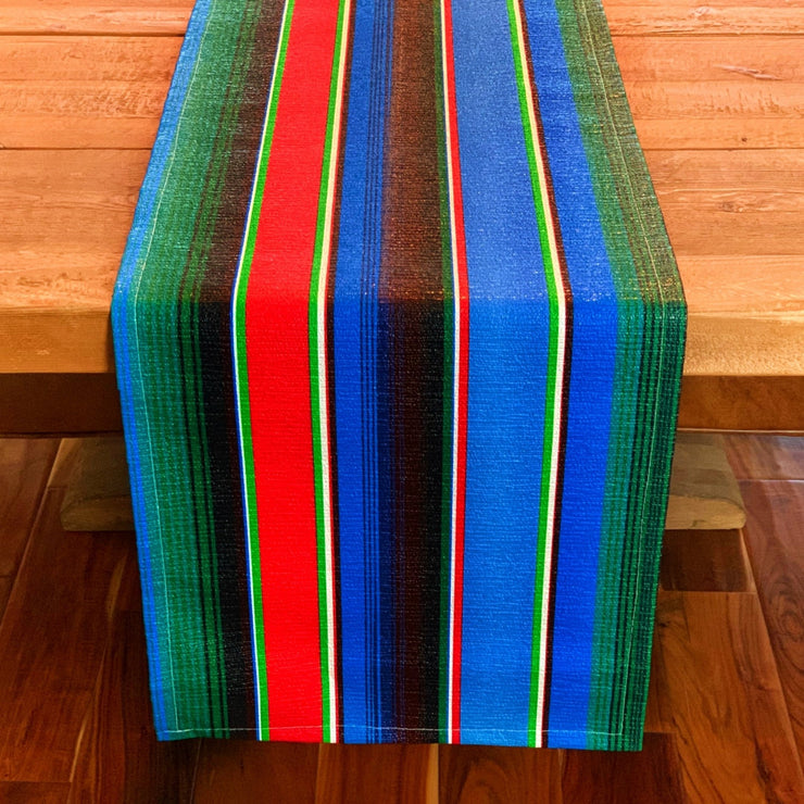 Above view: Multi-colored vertical striped patterned table runner on wooden table.