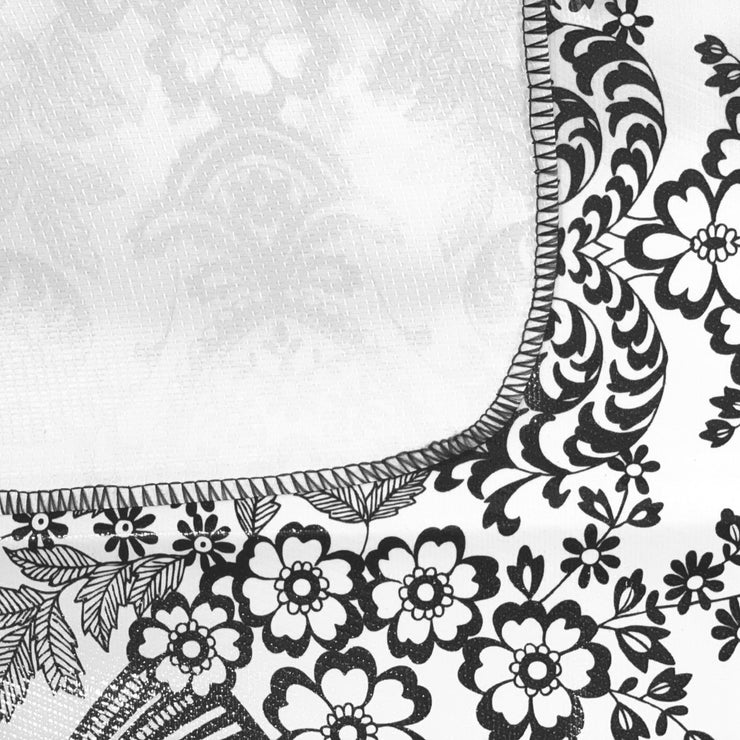 Close up:  Black floral print on white background tablecloth, white underside folded up to show contrast.