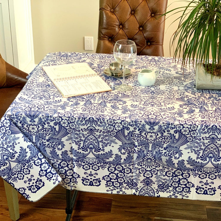 Above view:  Blue floral print on white background tablecloth covering table, open notebook displayed.