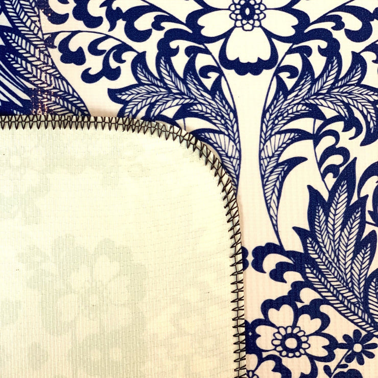 Close up: Blue floral print on white background tablecloth, white underside folded up to show contrast.