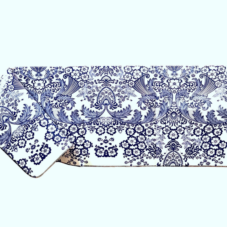 Side view: Blue floral print on white background tablecloth covering table.