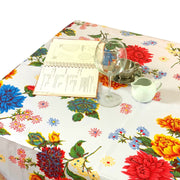 Above view: Multi-colored floral print on white background tablecloth, with open notebook displayed.