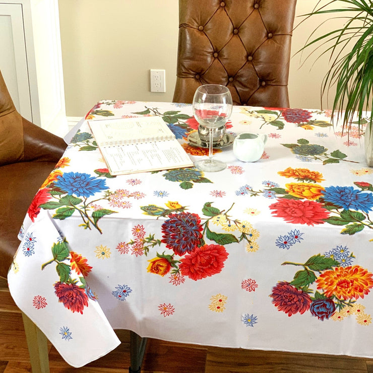 Side view: Multi-colored floral print on white background tablecloth, with open notebook displayed.