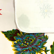 Close up: Multi-colored floral print on white background tablecloth, with white underside folded up to show contrast.