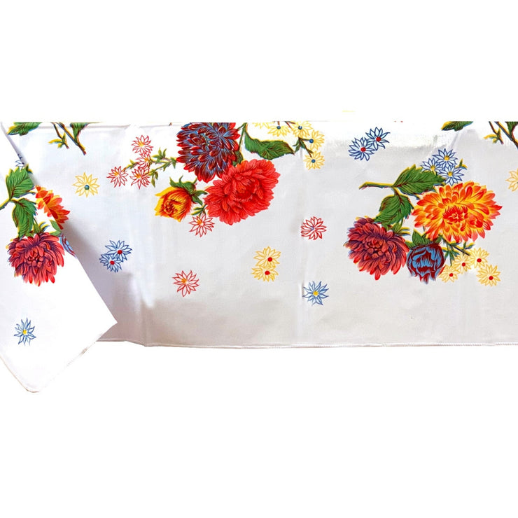 Side view: Multi-colored floral print on white background tablecloth covering table.