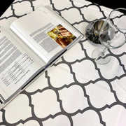 Above view:  Gray and white damascus print tablecloth covering table, with open book displayed. 