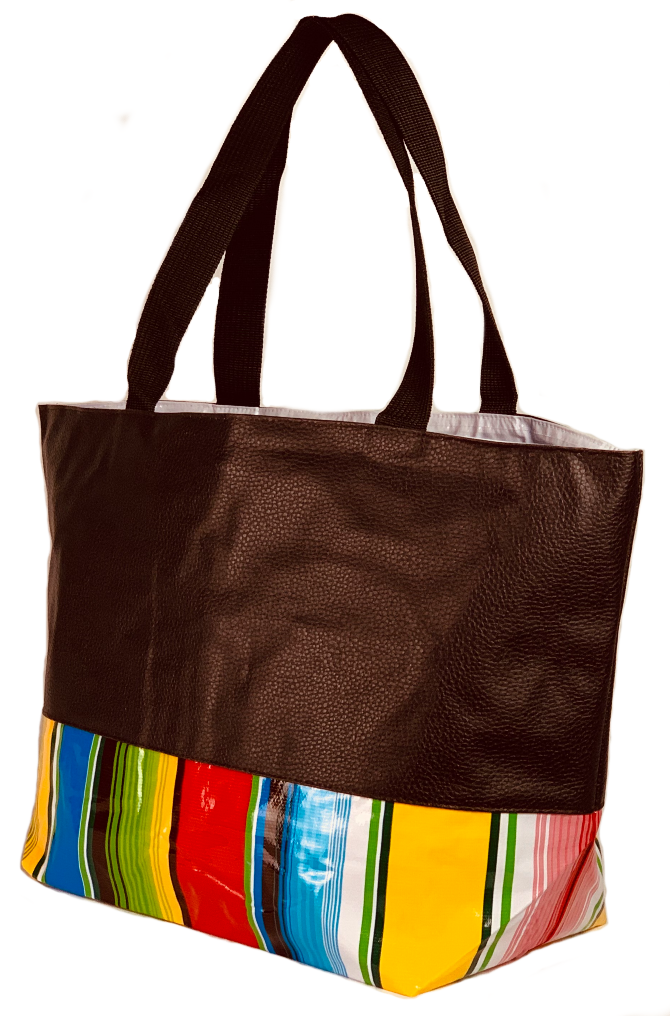 Angle view: Brown tote with multi-color striped pattern base with brown grab handles.