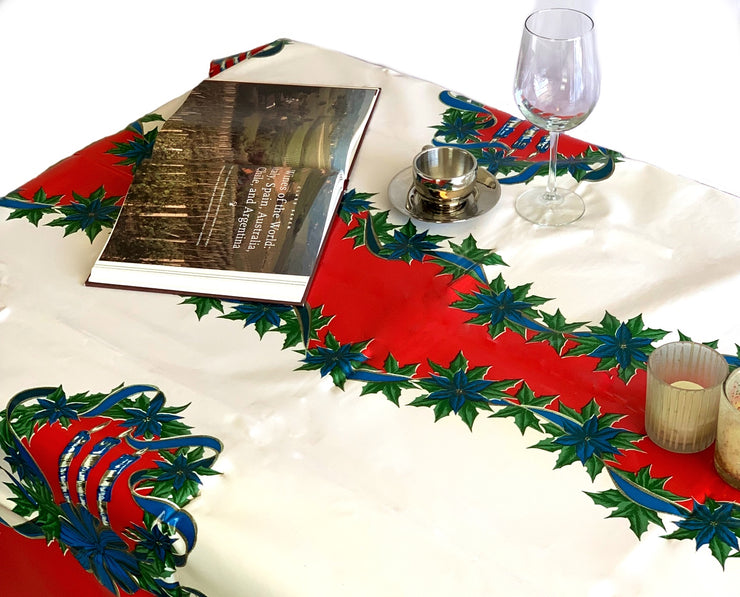 Above view: Blue ribbons with poinsettia edging on white and red striped background tablecloth, open book displayed.