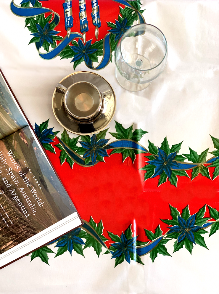 Above view: Blue ribbons with poinsettia edging on white and red striped background tablecloth, open book displayed.