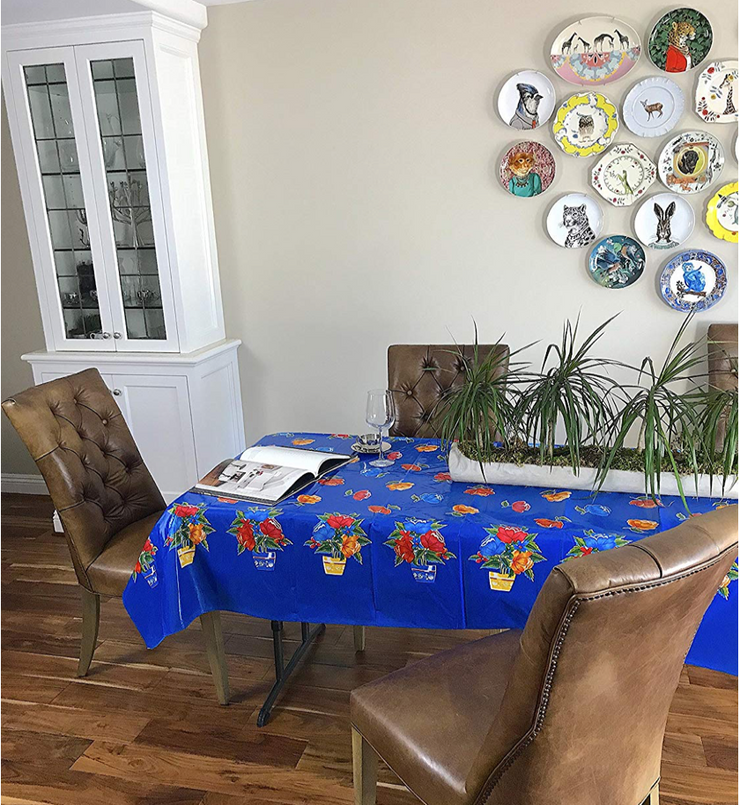 Angle view: Multi-colored flower print on blue background tablecloth, opened book displayed and potted plant centerpiece.