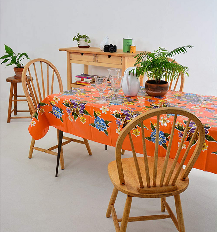 Angle view: Multi-colored floral print on orange background tablecloth, with potted plant centerpiece.
