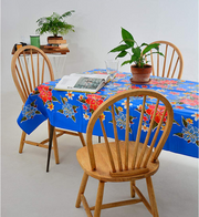 Angle view: Multi-colored floral print on blue background tablecloth, with potted plant centerpiece.