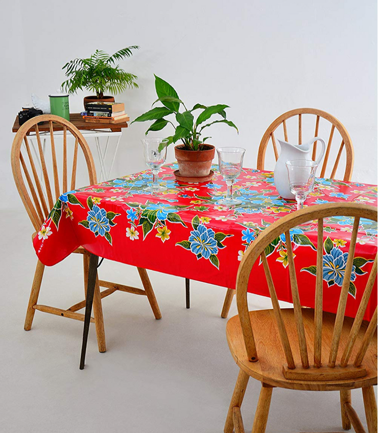 Angle view: Multi-colored floral print on red background tablecloth, with potted plant centerpiece.