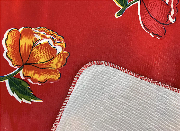 Close up: Multi-colored flower print on red background tablecloth with white underside folded up to show contrast.