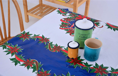 Above view: Red ribbons with poinsettia edging on white and blue striped background tablecloth, with jars centerpiece.