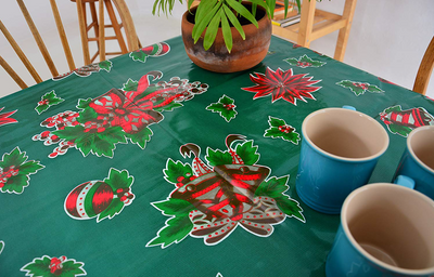 Above view: Multi-colored Christmas holiday print on green background tablecloth, with potted plant centerpiece.