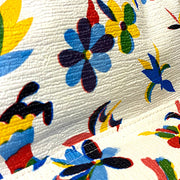 Close-up: Otomi backpack with multi-colored flower/animal print on white background.