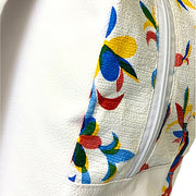 Partial back view: Otomi backpack with multi-colored flower/animal print on white background and white back panel.