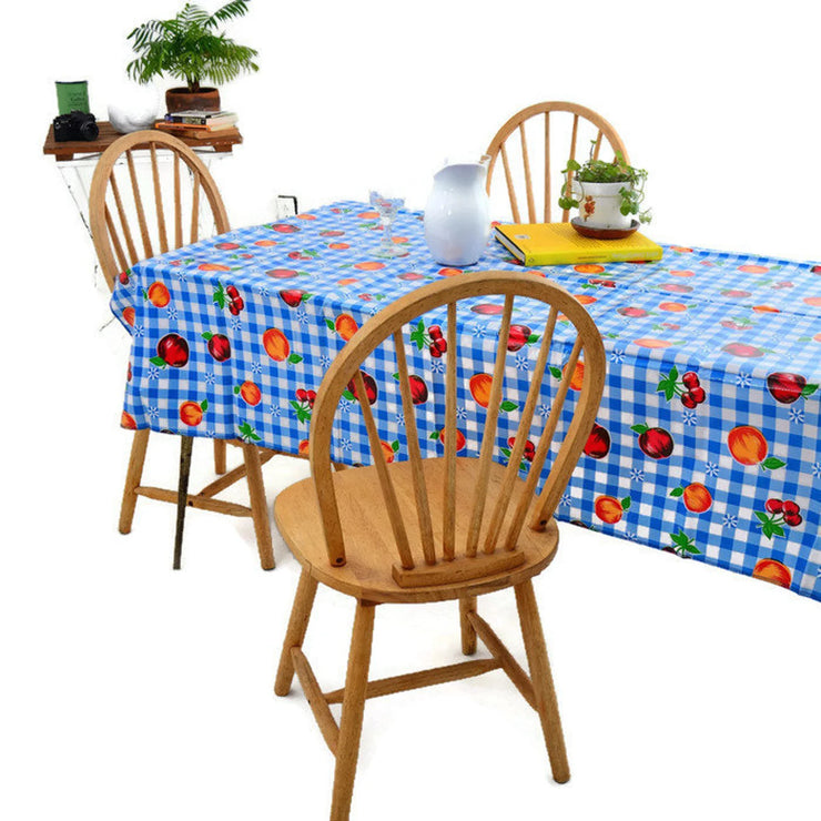 Angle view: Multi-colored fruit print on blue and white checkered pattern background tablecloth, with potted plant centerpiece.