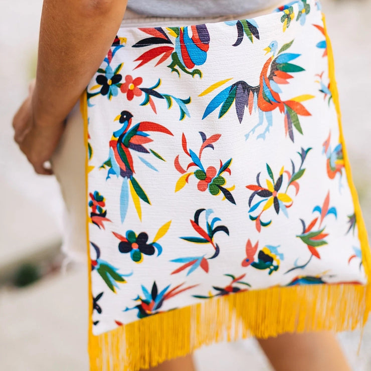 Back view: Woman wearing Otomi Crossbody Bag, multi-colored flower/animal print with yellow fringe.