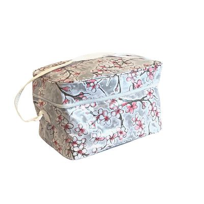 Angle view: Cherry blossom print on gray background lunchbox with white strap handle.