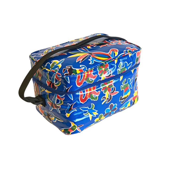 Angle view: Multi-colored animal/floral print on blue background lunchbox with black strap handle. 