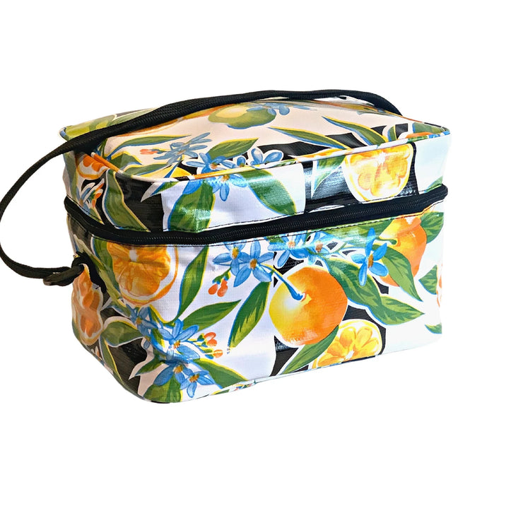 Angle view: Multi-colored orange fruit and blossom print on black and white striped background with black strap handle. 