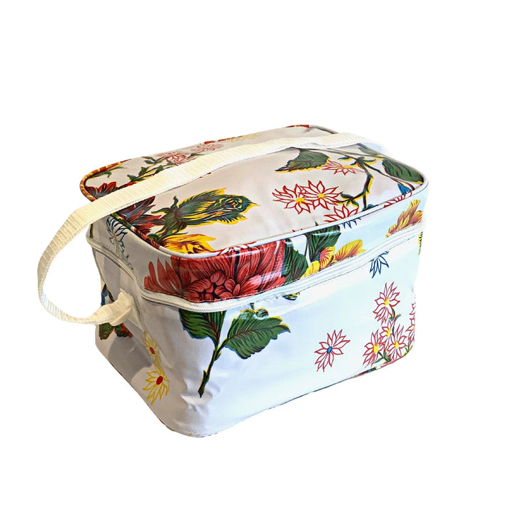 Angle view: Multi-colored floral print on white background lunchbox with white strap handle. 